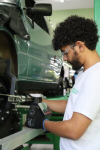 Mecânico automotivo especializado realizando a checagem dos itens de manutenção preventiva em um veículo no elevador.