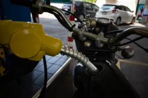 Abastecimento de motocicleta em posto de combustível, com bico de gasolina inserido no tanque da moto.