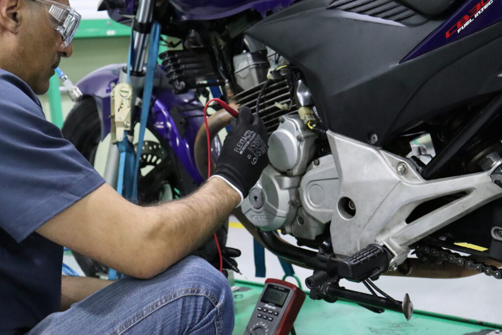 Mecânico de motos realizando a manutenção de uma motocicleta em uma oficina.