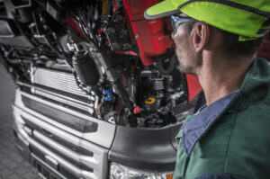 Mecânico especializado realizando o ajuste e a manutenção em um motor diesel em uma oficina de linha pesada.