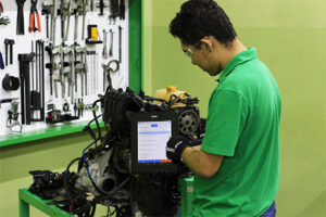 Eletricista automotivo realizando o diagnóstico no sistema elétrico de um veículo.
