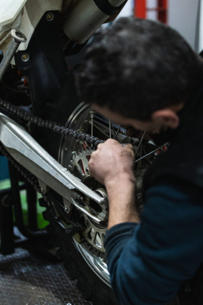 Mecânico especializado inspecionando e trocando a pastilha de freio de uma motocicleta em uma oficina.