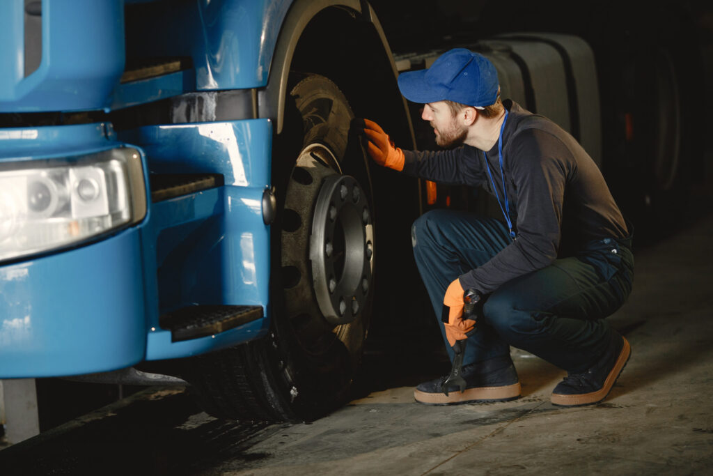 Mecânico de caminhão realizando inspeção e diagnóstico no motor diesel de um veículo pesado em uma oficina mecânica.